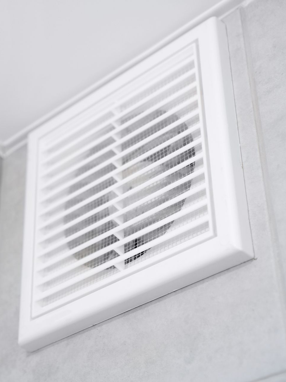 Grille d'aération carrée blanche fixée au mur.
