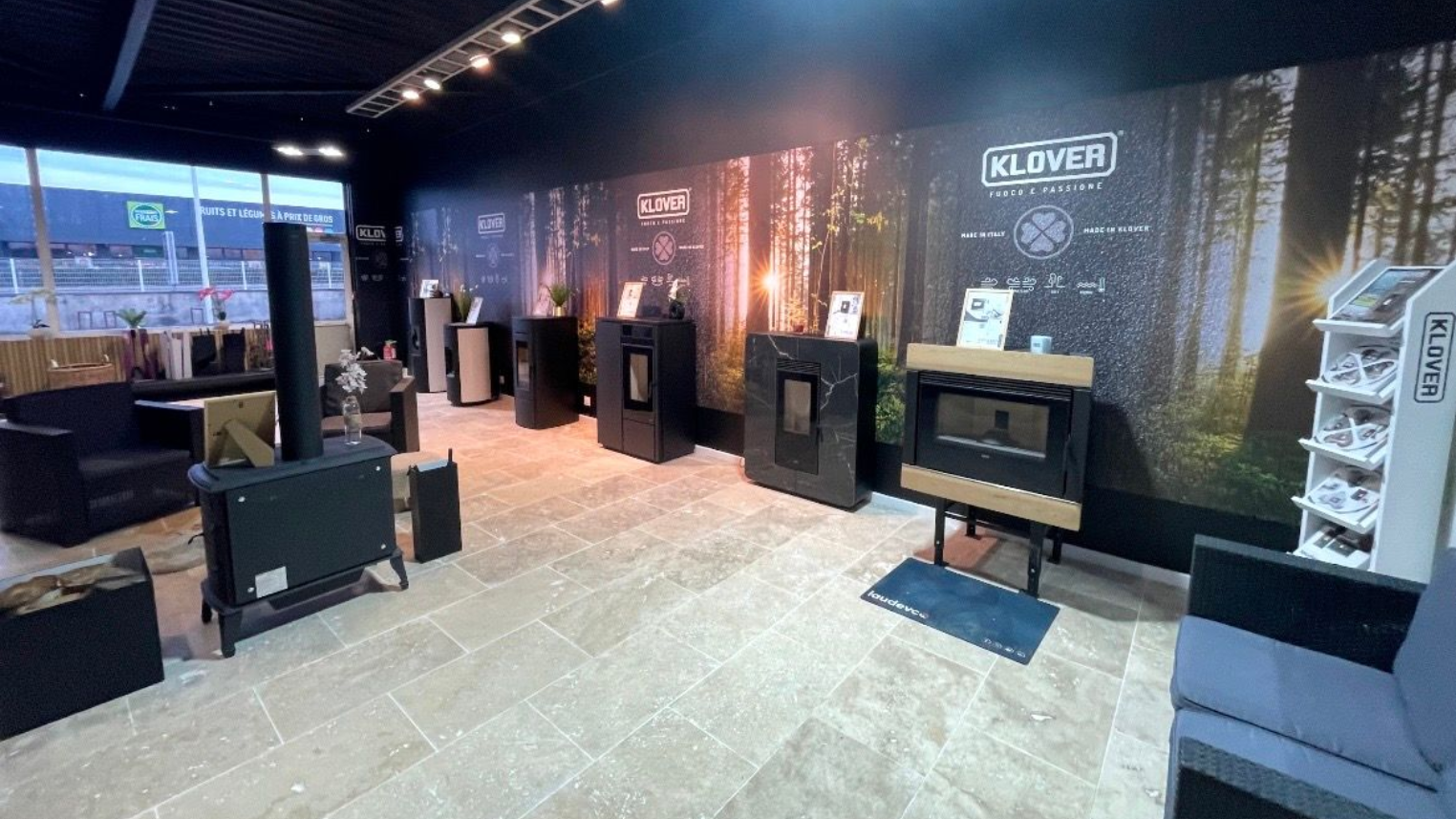 Pièce confortable avec poêle allumé, fauteuil en osier près de la fenêtre, plante d'intérieur et lampe.