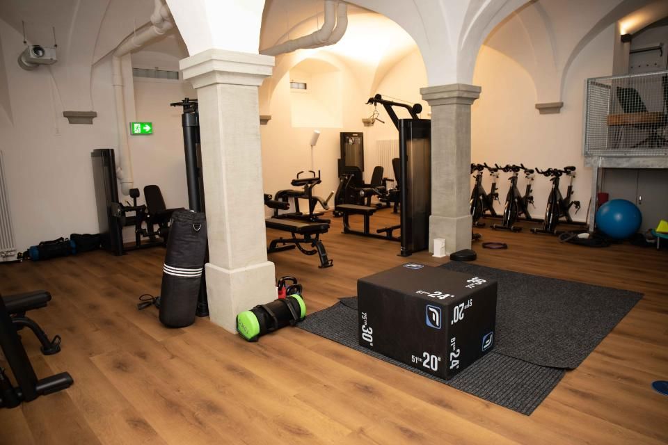 Innenraum einer Turnhalle mit Trainingsgeräten auf Holzboden unter einer gewölbten Decke.