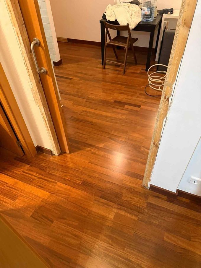 Pasillo con suelo de madera que conduce a una pequeña mesa y una silla, con una cesta de la ropa sucia a la derecha.