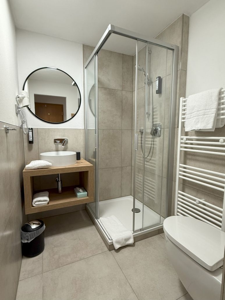 Kleines, modernes Badezimmer mit Glasdusche, Waschbecken, Toilette und Handtuchhalter.