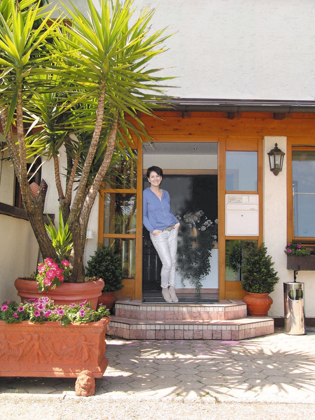 Hotelzimmer mit Einzelbett, Schreibtisch, Stuhl, Fenster, Holzvertäfelung und einem kleinen Teppich.