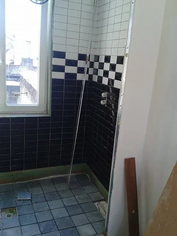Douche avec sol en pavé et mur en faïence