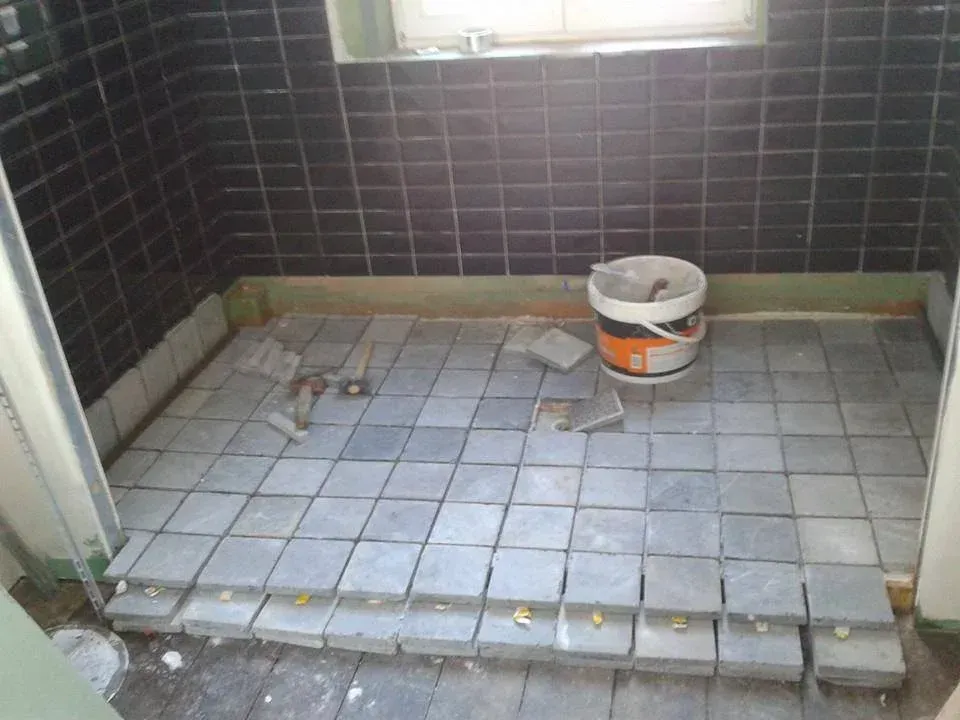 Pose de pavés gris sur le sol de la douche