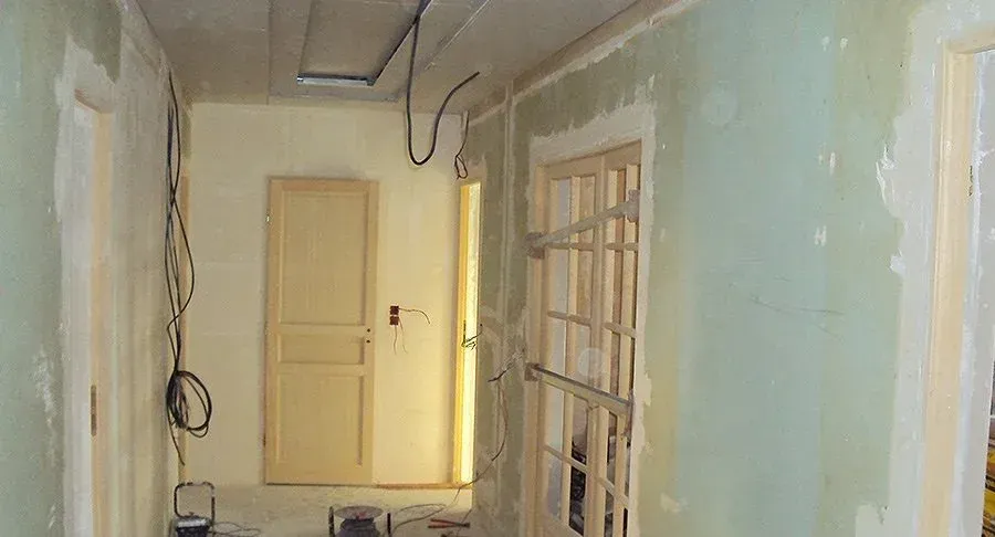 Couloir avec des cloisons abîmées, avant les travaux