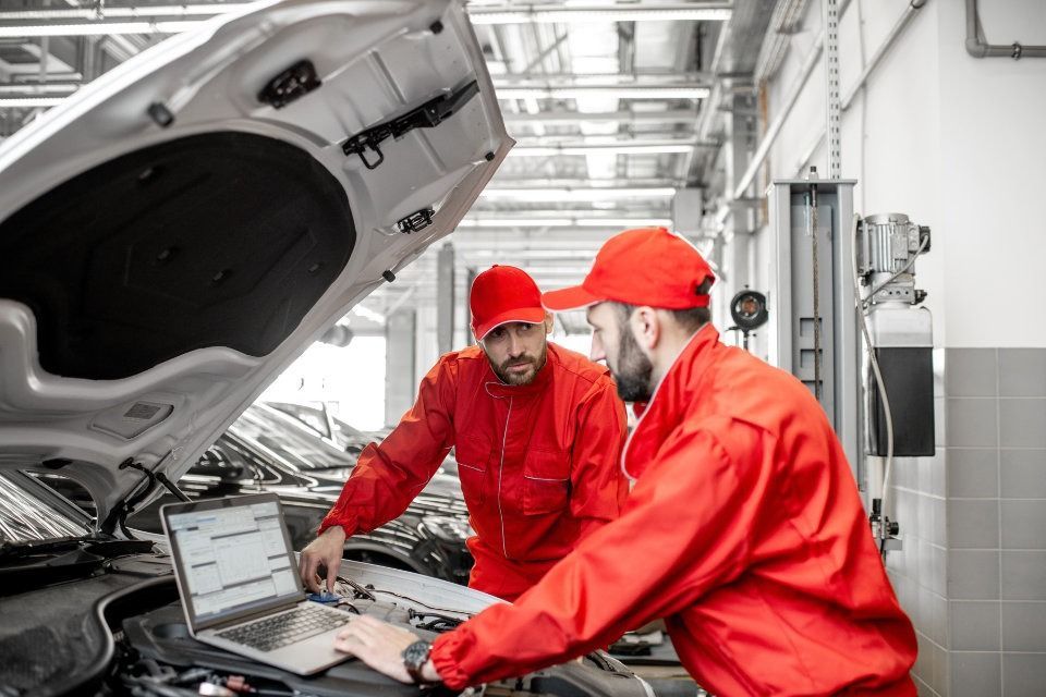 Dos mecánicos están trabajando en un coche en un garaje.