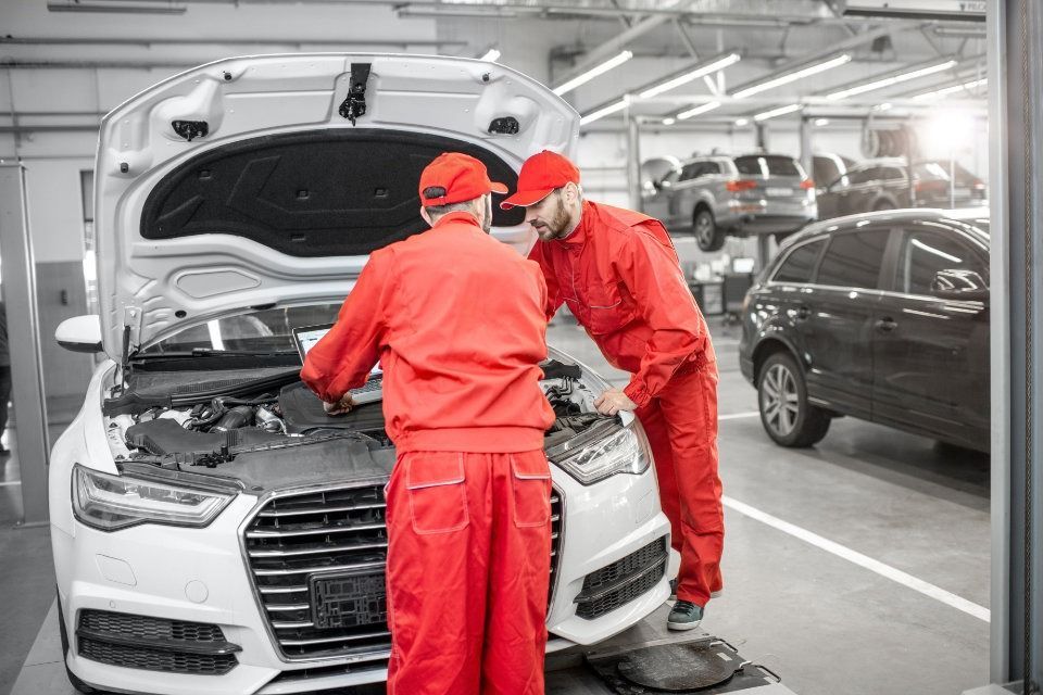 Dos mecánicos están trabajando en un coche en un garaje.