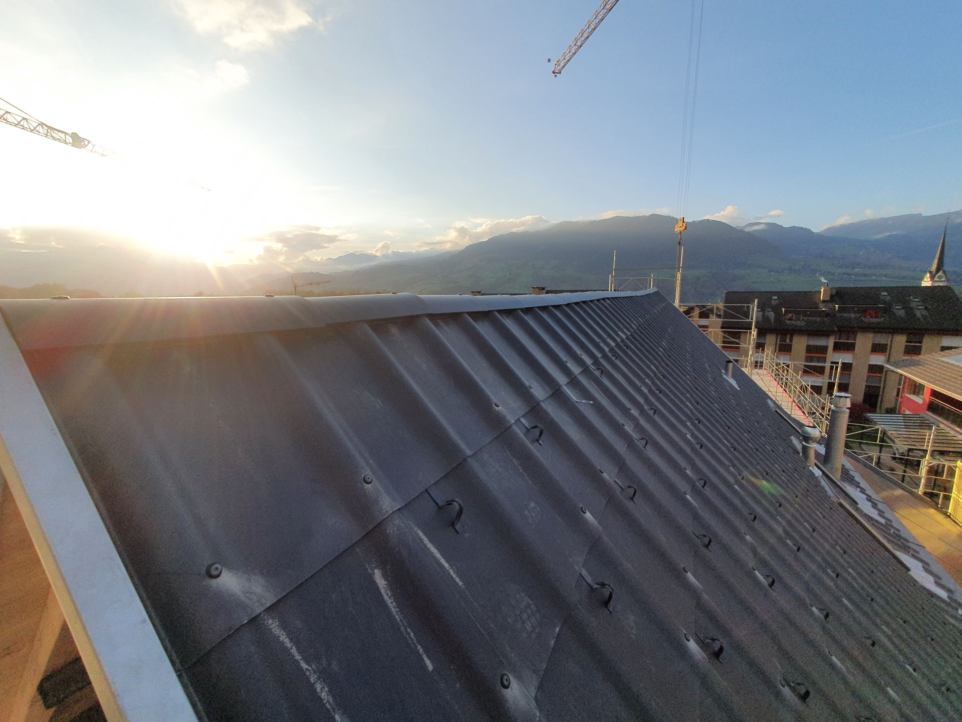 Ein Mann steht auf einem Dach neben einer Leiter, Sepp Wagner GmbH