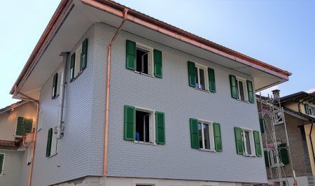 Ein großes weißes Gebäude mit grünen Fensterläden, Sepp Wagner GmbH