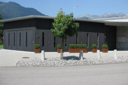 Ein Gebäude mit einem Baum davor und Bergen im Hintergrund, Sepp Wagner GmbH