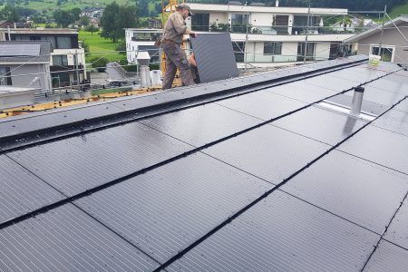 Ein Mann steht auf einem Dach mit Solarmodulen, Sepp Wagner GmbH