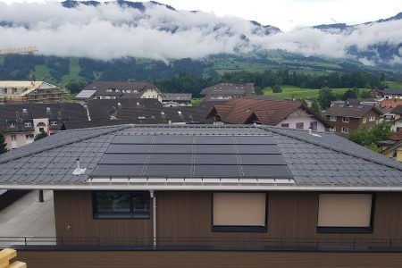 Ein Haus mit Solarzellen auf dem Dach und Bergen im Hintergrund, Sepp Wagner GmbH