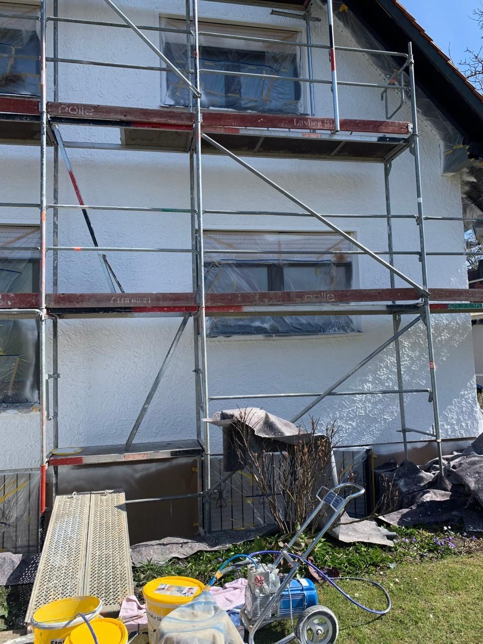 Ein Haus wird gestrichen, davor steht ein Gerüst.