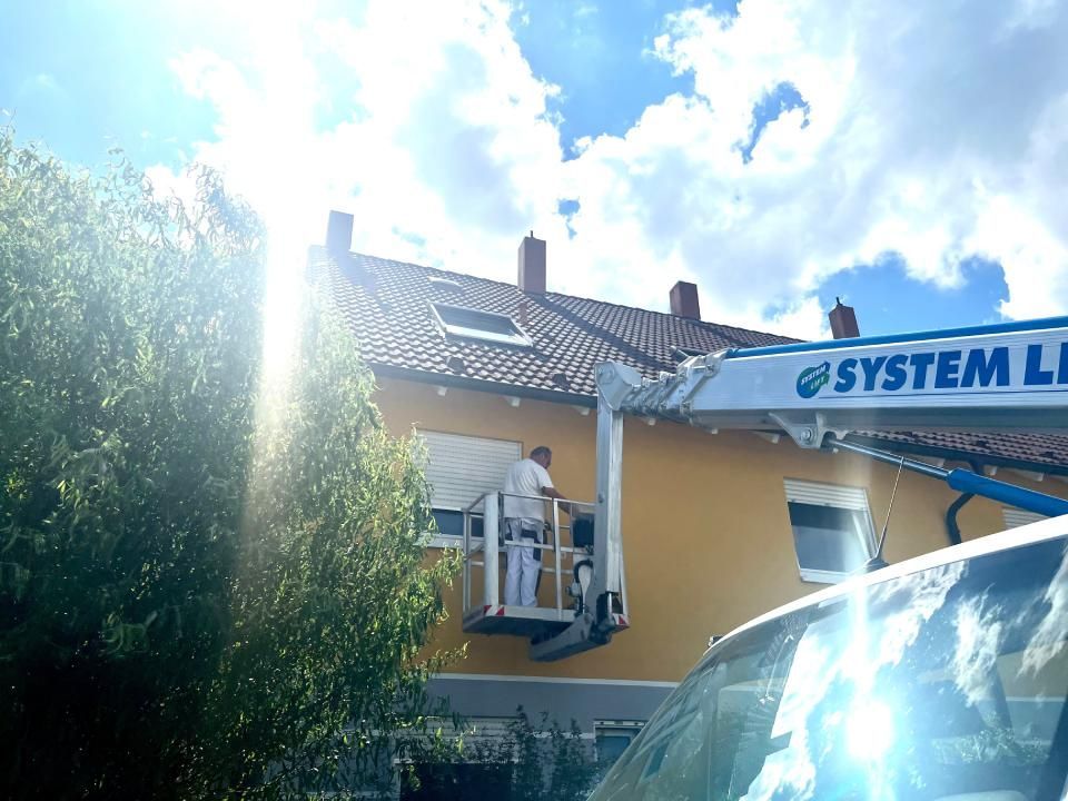 Ein Mann streicht ein Gebäude mit einem Systemaufzug