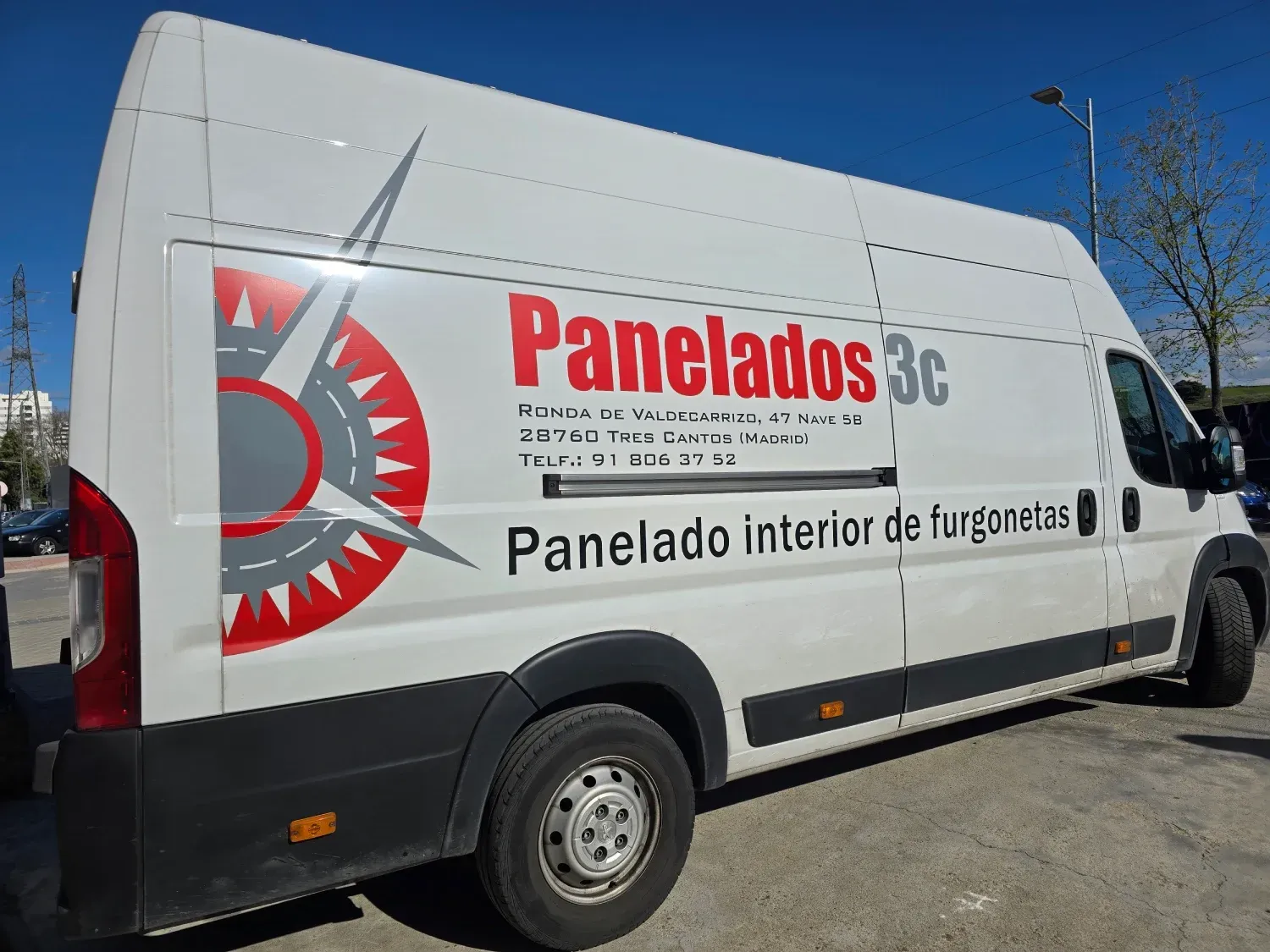 Una camioneta blanca con paneles 3c escrito en el costado está estacionada en un estacionamiento.