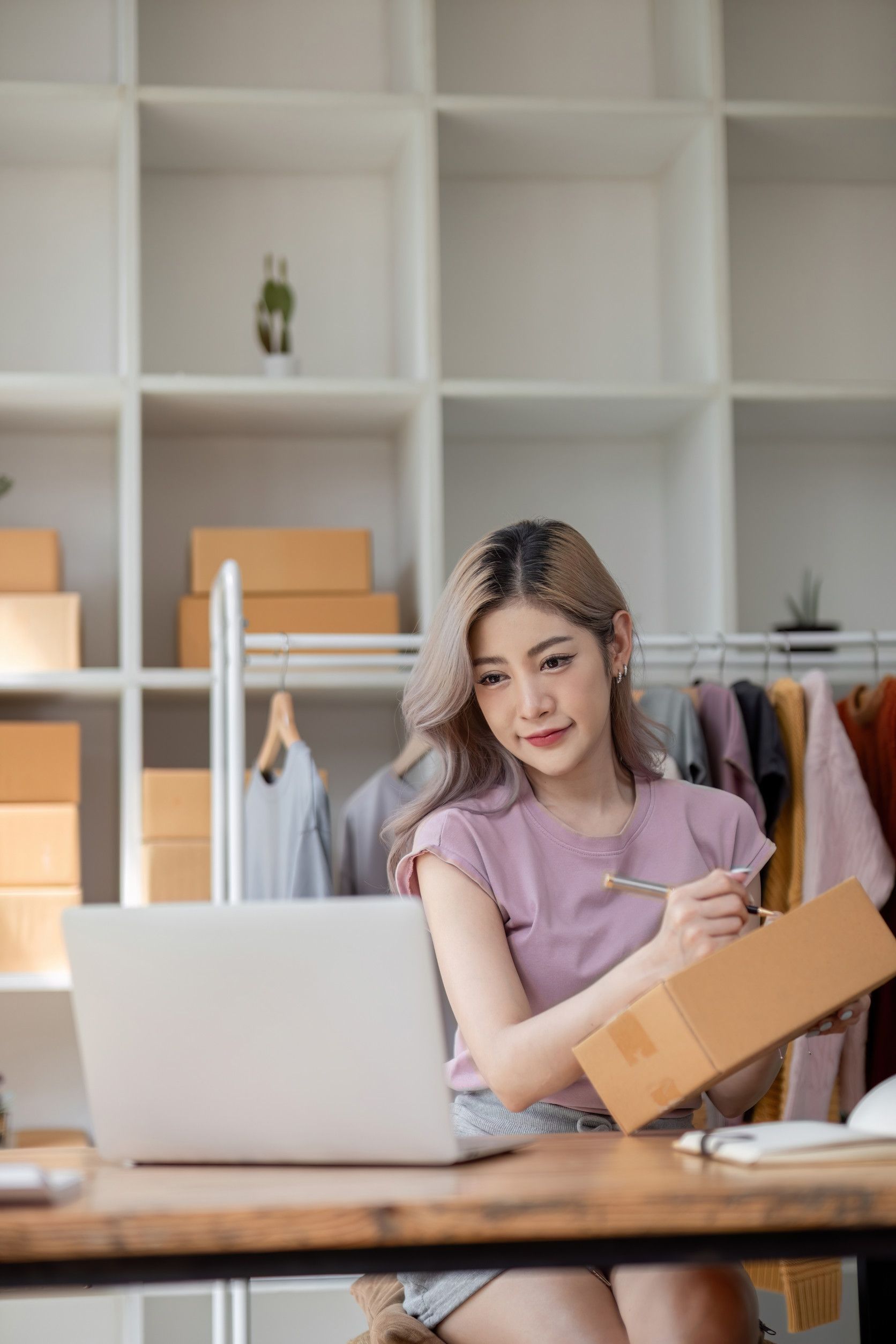 Una mujer está sentada en un escritorio con una computadora portátil y una caja.