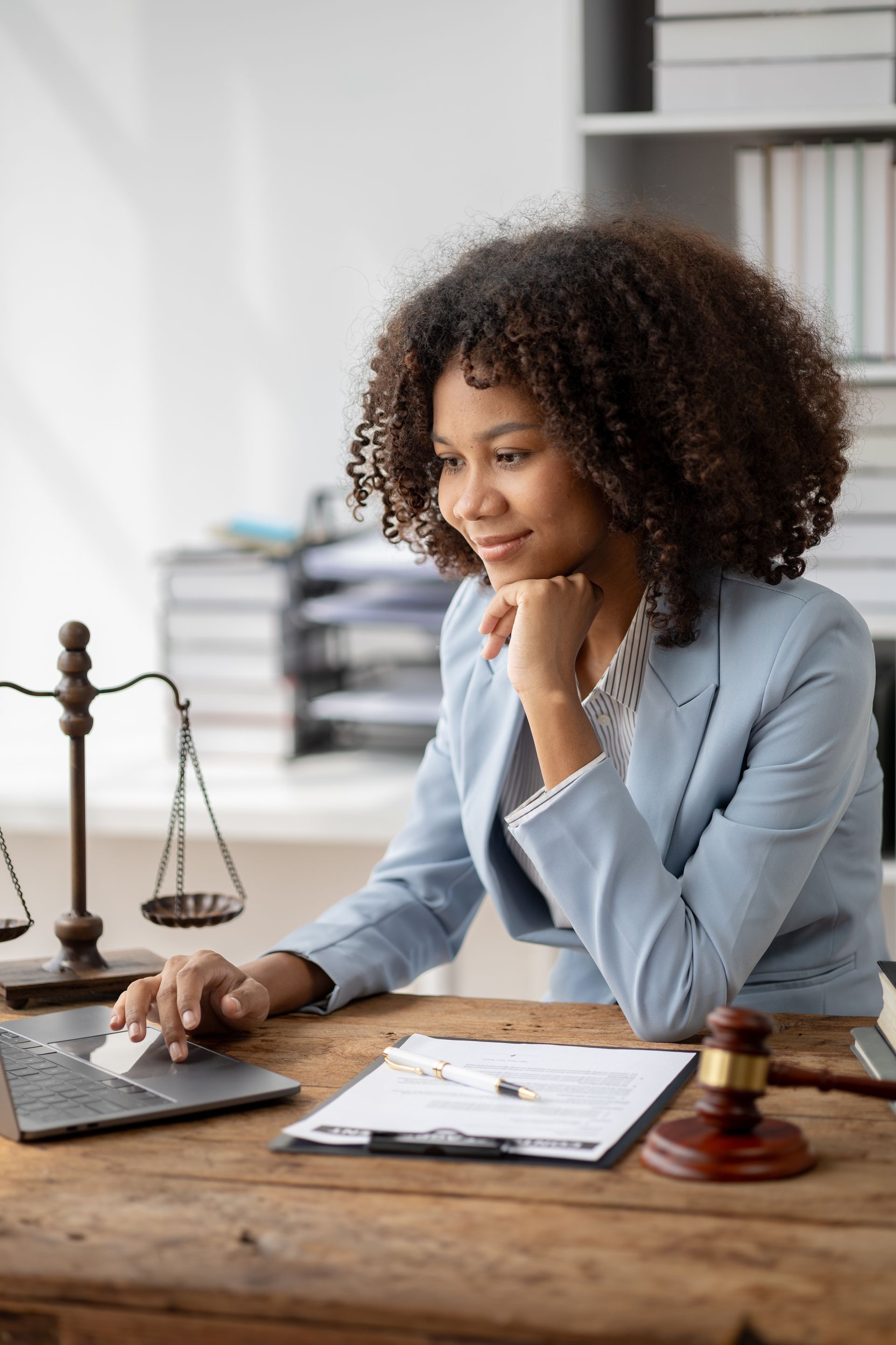 Une femme utilise un ordinateur portable avec une règle juridique, un maillet et des documents posés sur un bureau