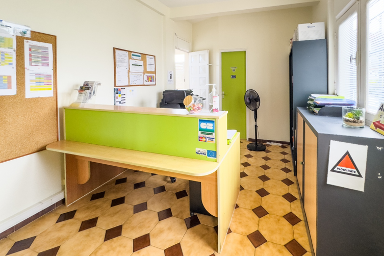 Comptoir d'accueil dans un bâtiment aux couleurs vertes et beiges