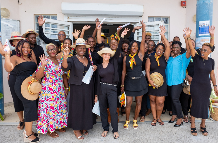 Groupe de personnes souriantes, vêtues de noir et de jaune, à l'extérieur d'un bâtiment