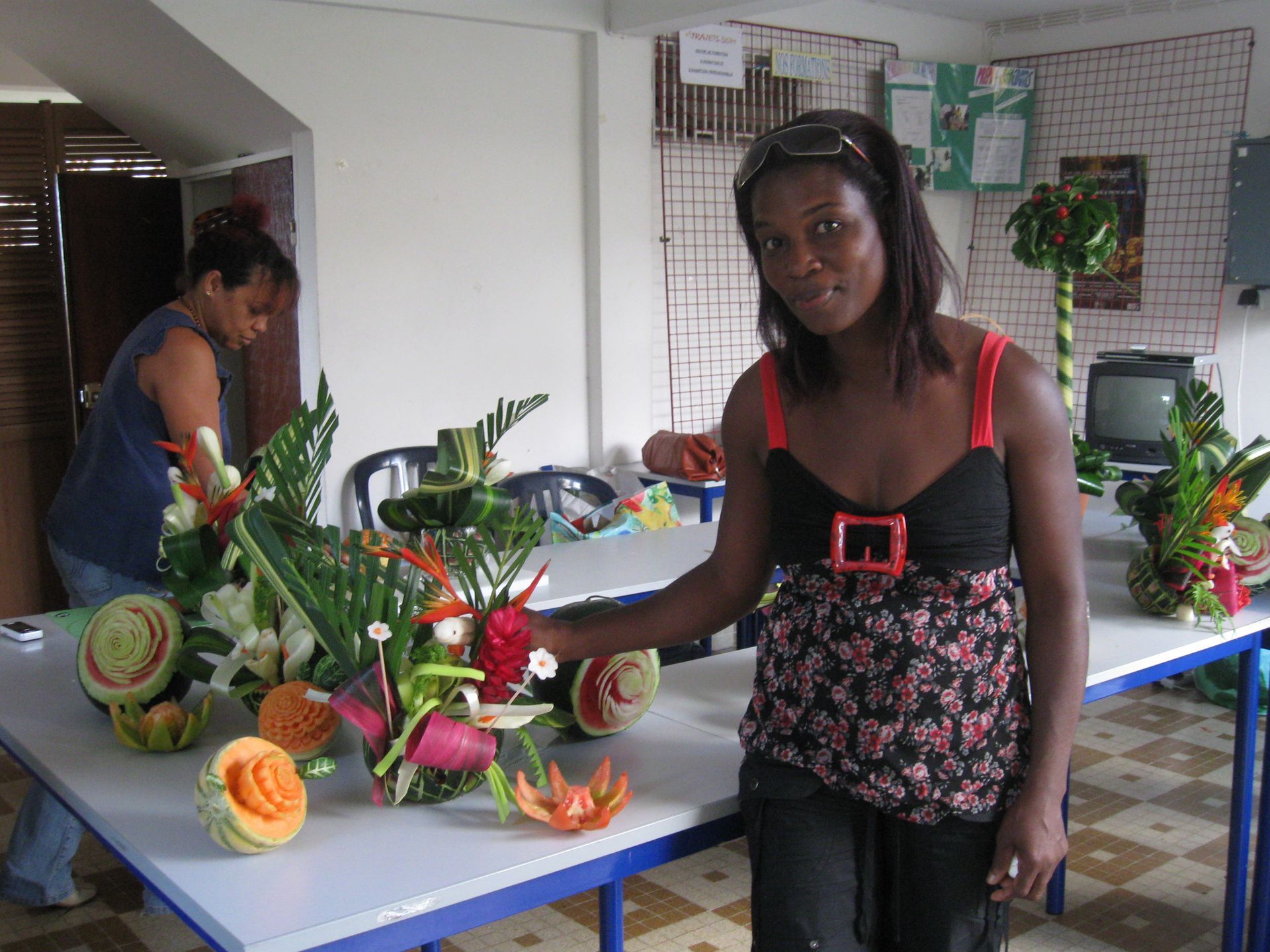 Une femme disposant des fruits sculptés sur une table