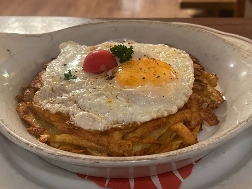 Kartoffelrösti mit Spiegelei und Kirschtomate in einer weissen Schüssel.