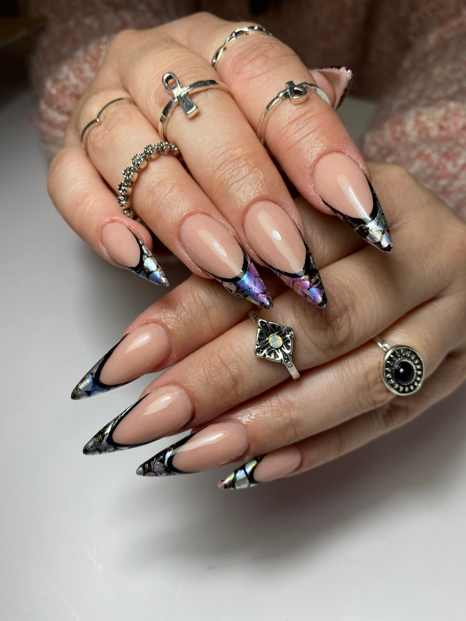 Manos con uñas en forma de almendra, diseño de remolinos en color blanco y burdeos.