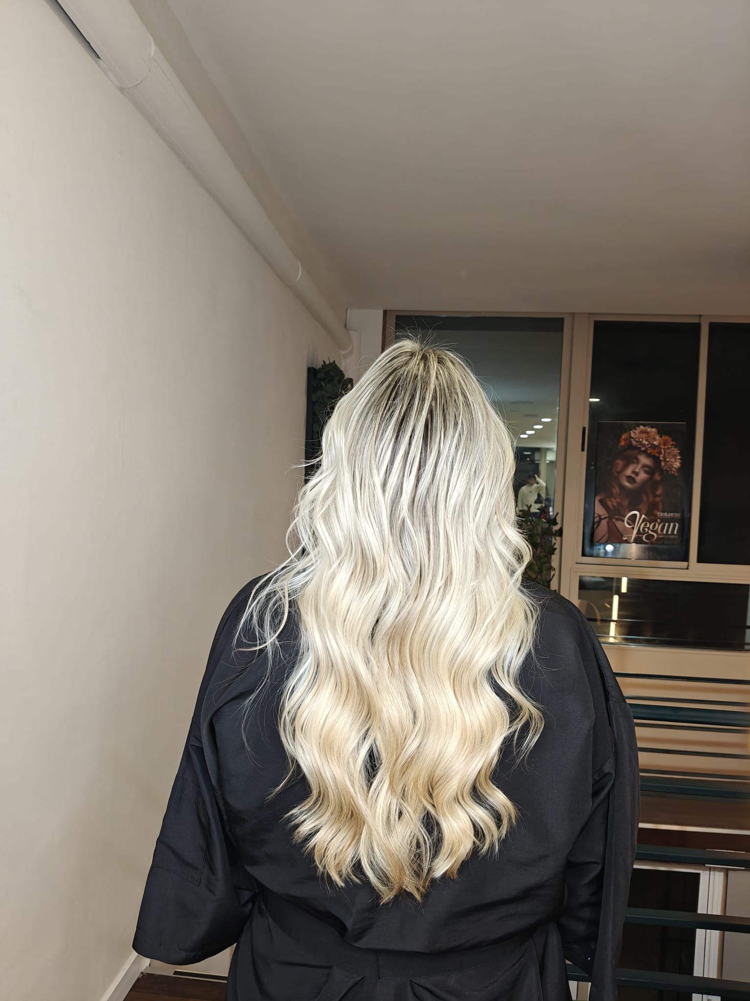 Mujer con cabello largo y negro, con los brazos en alto, de pie sobre un fondo rosa.