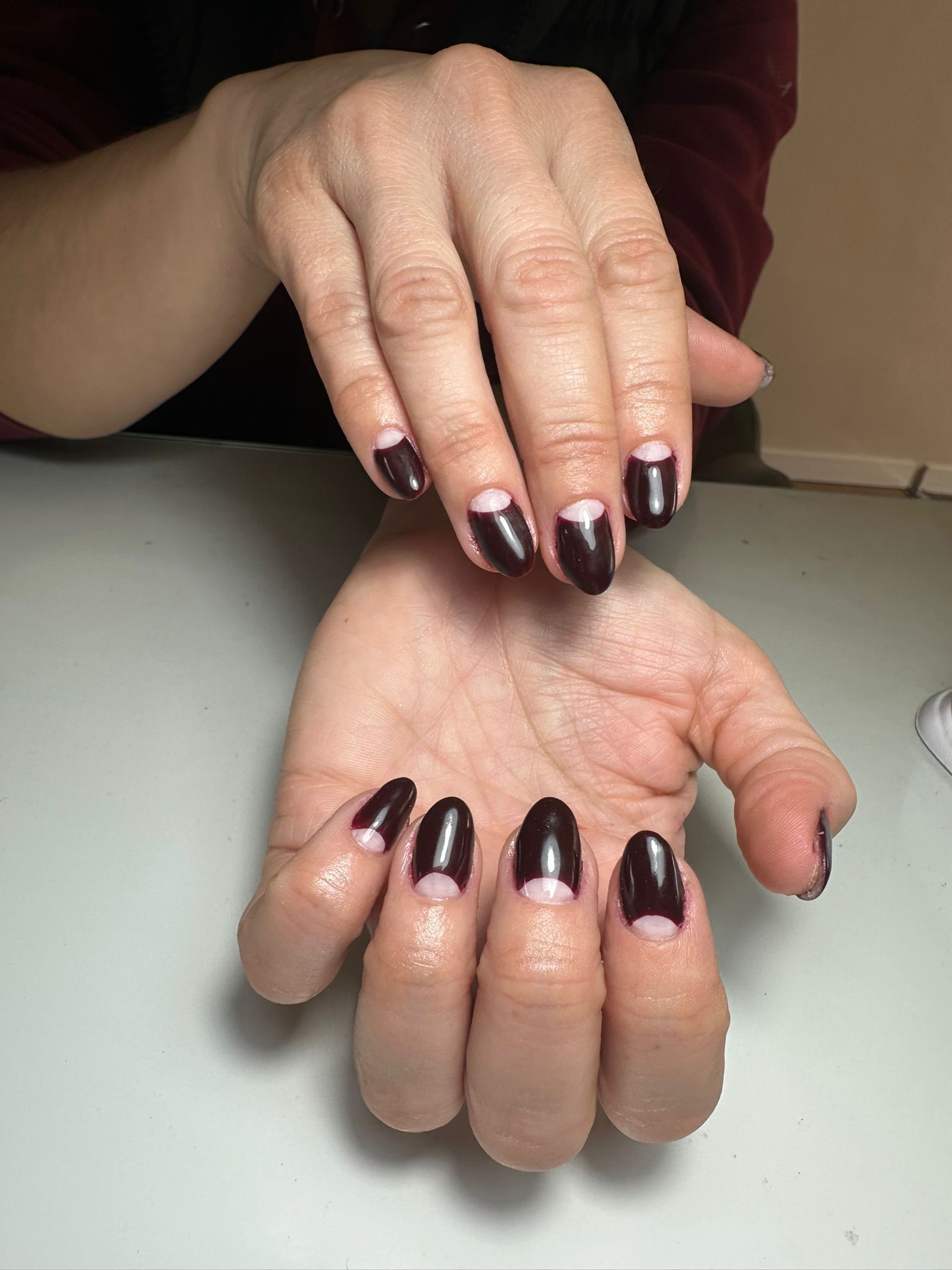 Manos con uñas en forma de almendra, algunas de color azul marino y otras de color rosa claro con puntos azul marino.