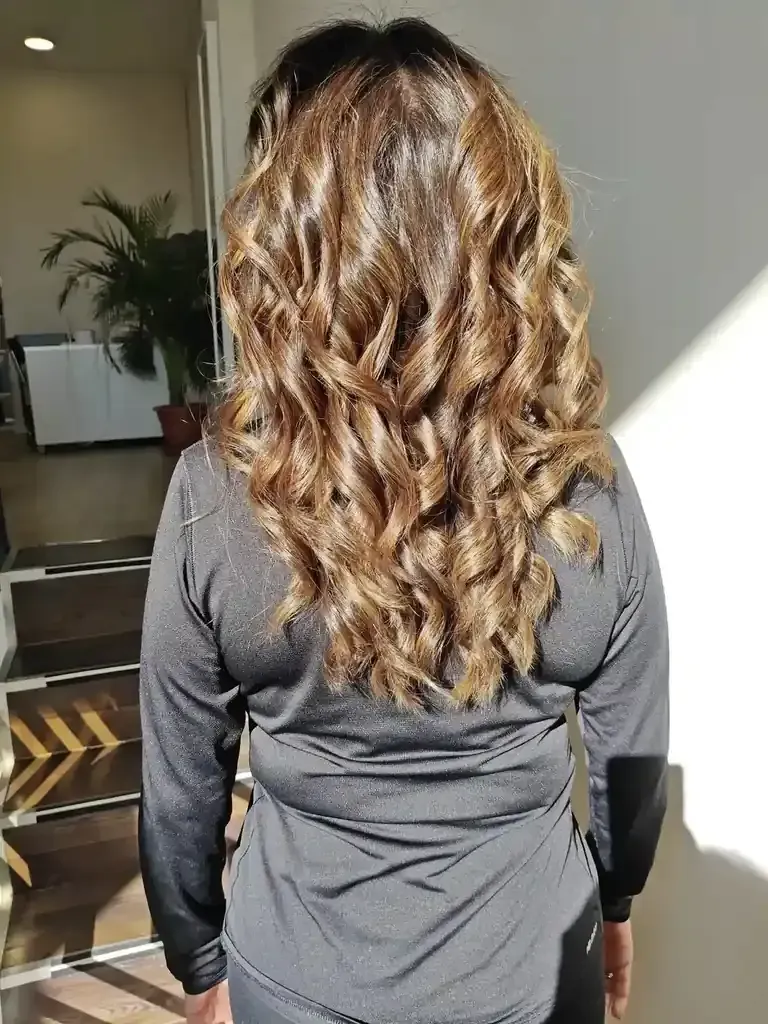 Mujer con cabello largo y ondulado de color castaño y rubio.