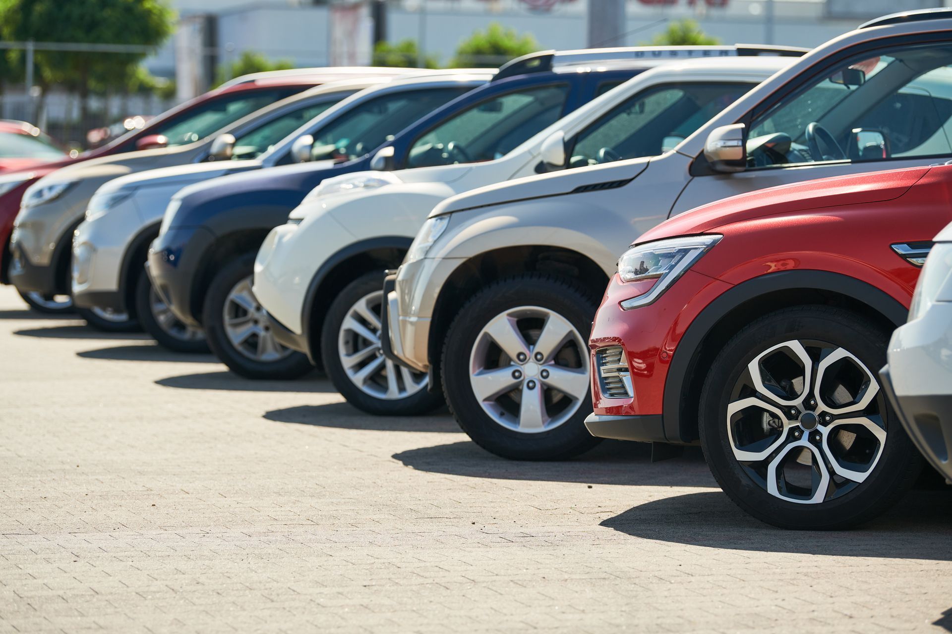 Eine Reihe geparkter Autos auf dem Parkplatz eines Autohändlers, darunter ein roter SUV im Vordergrund