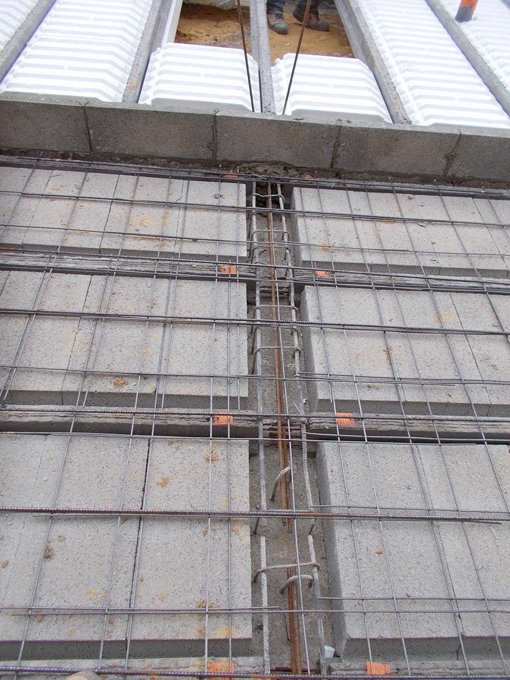 Scène de construction montrant un système de plancher en béton armé avec un treillis métallique posé sur des inserts en blocs creux.