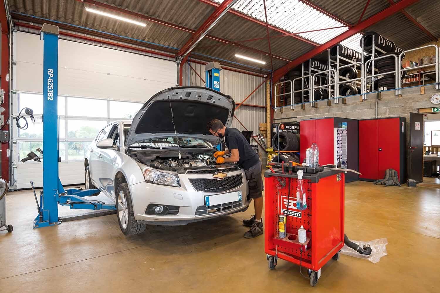 Garagiste qui regarde le moteur d'une voiture