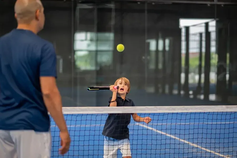 Un hombre y un niño están jugando al tenis en una cancha.