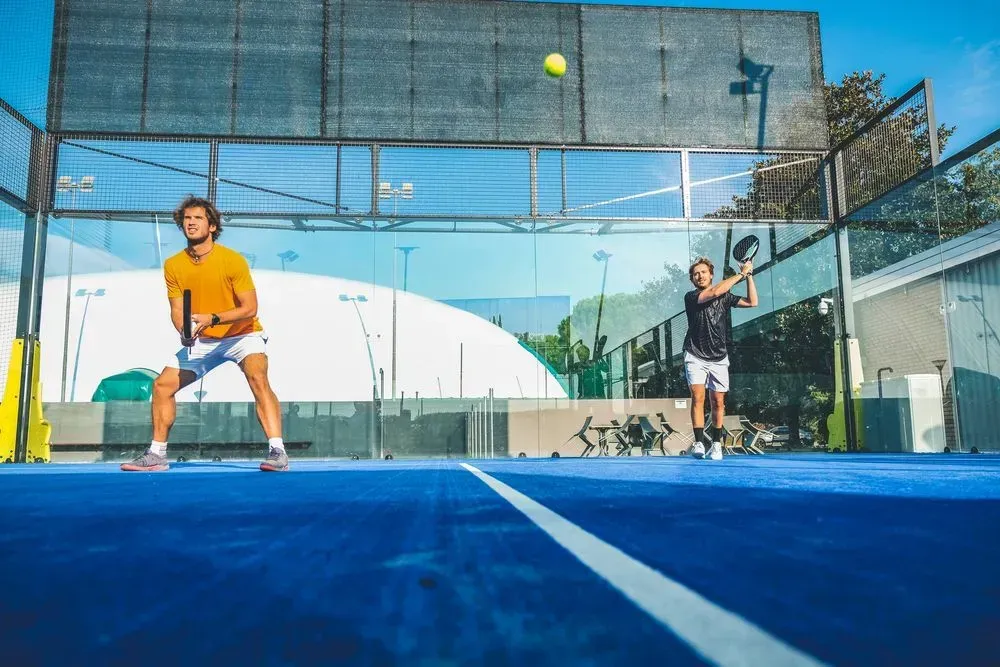 Dos hombres están jugando al pádel en una cancha azul.