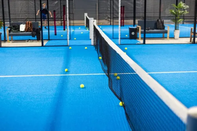 Una cancha de tenis con una red y pelotas de tenis sobre ella.