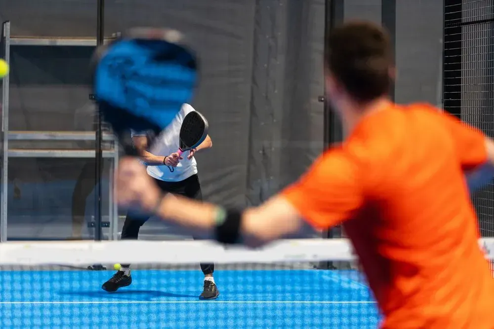 Un hombre y una mujer están jugando al pádel en una cancha.