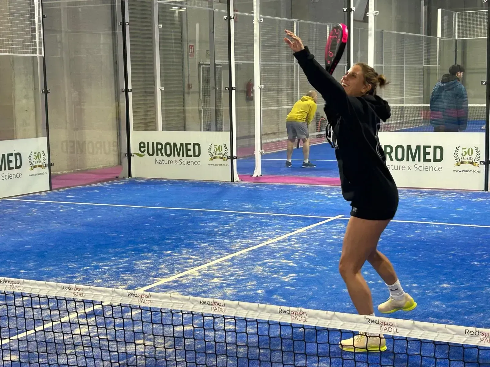 Una mujer juega un partido de pádel en una cancha patrocinada por buromed