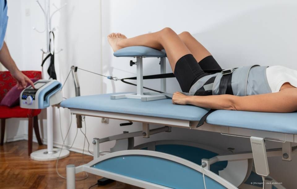 Person erhält auf einem Spezialtisch eine Dekompressionstherapie der Wirbelsäule. Ein Mitarbeiter des Gesundheitswesens stellt die Maschine ein.