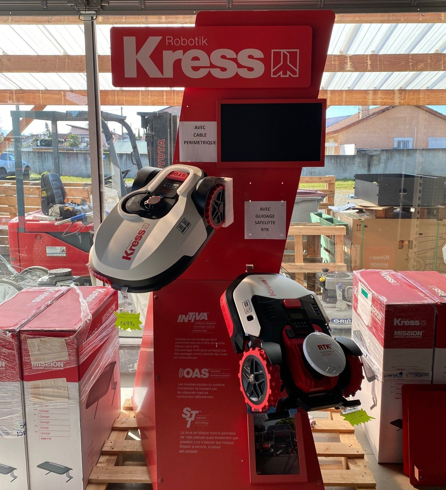 Présentation de tondeuses à gazon robotisées Kress dans un magasin ; tondeuses rouges et blanches avec un panneau rouge.