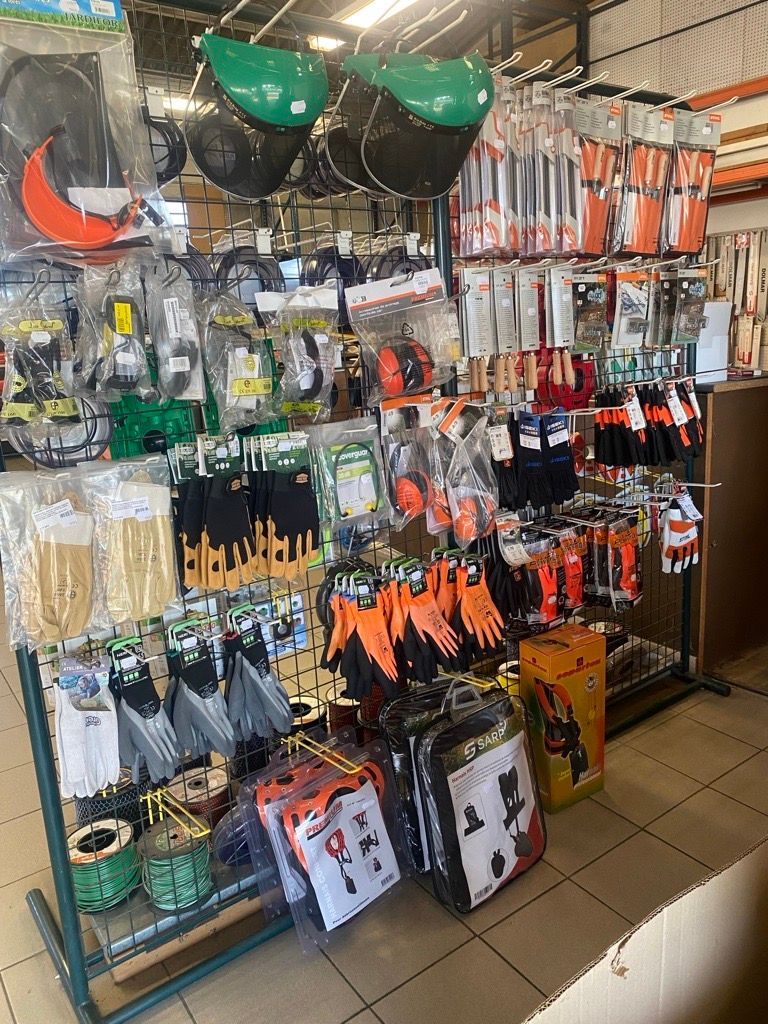 Personne utilisant un coupe-bordures dans une cour herbeuse, brouette en arrière-plan.