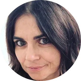 Mujer de cabello oscuro y ojos marrones mirando hacia el espectador, sonriendo levemente.