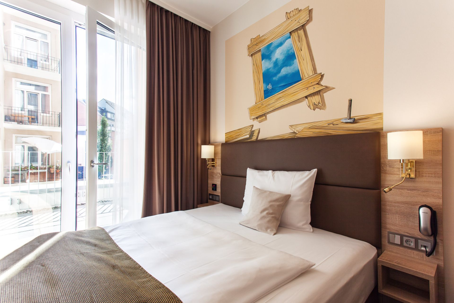 Hotelschlafzimmer mit Bett, Fenster und dekorativer Wandkunst.