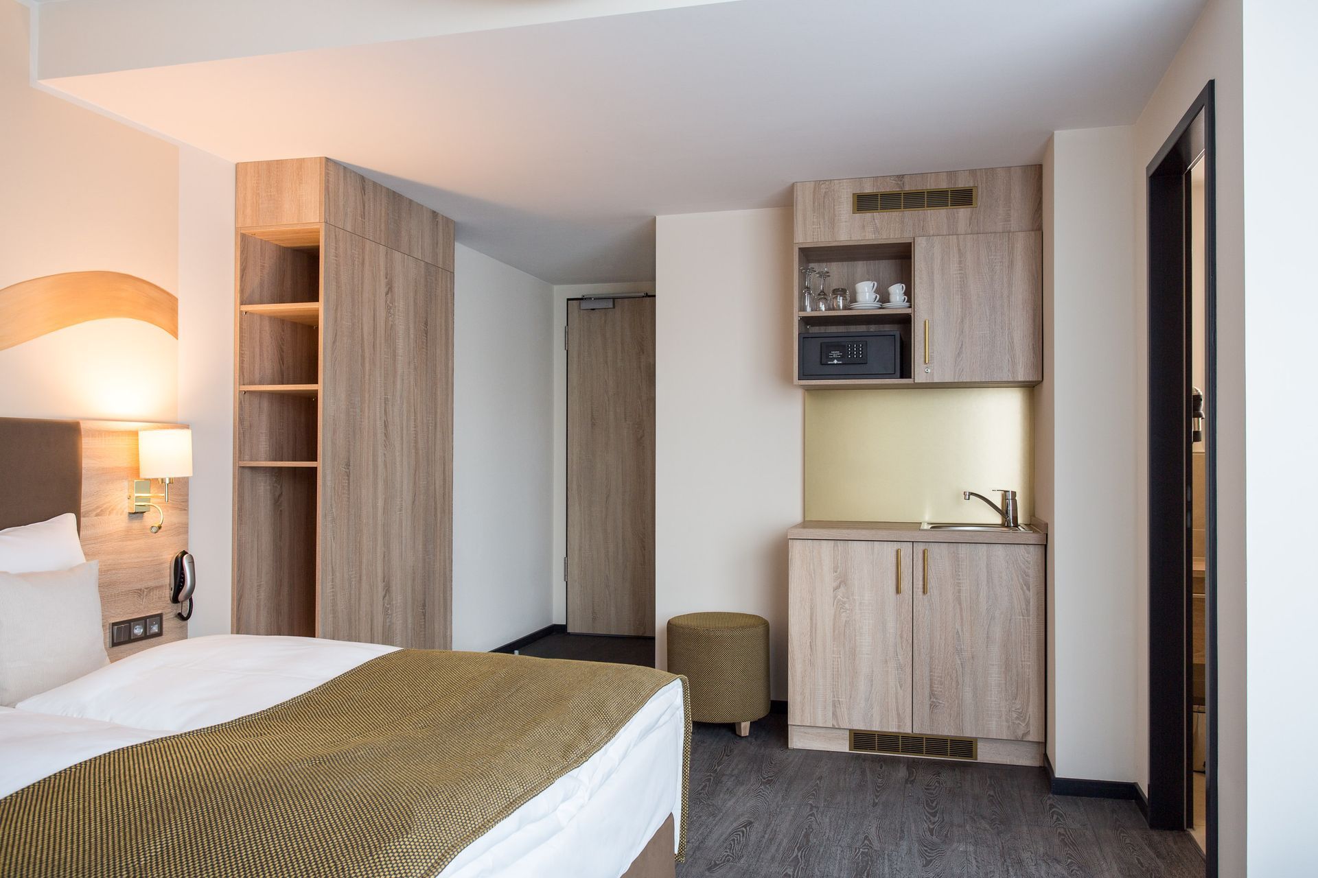 Hotelzimmer mit Bett, Kleiderschrank und Küchenzeile.