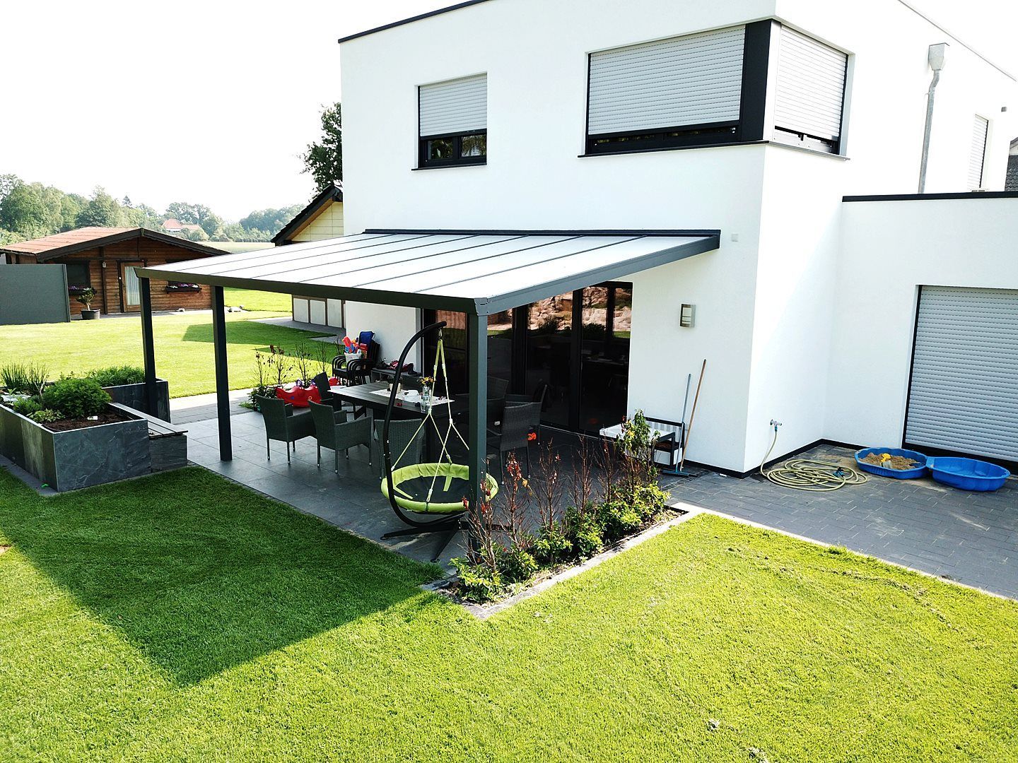 Ein weißes Haus mit einer überdachten Terrasse davor.