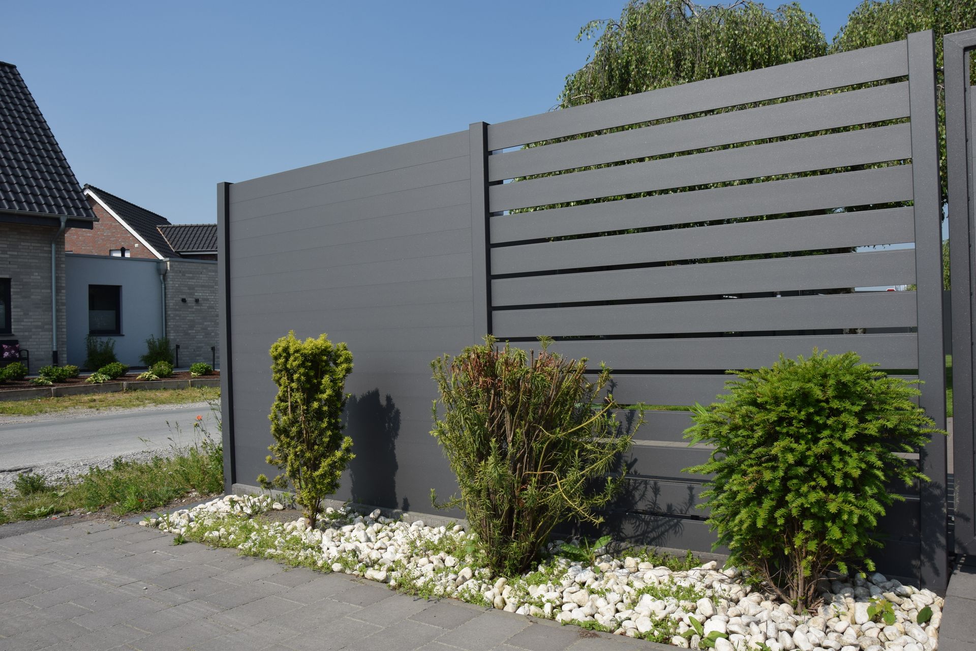 Ein Zaun mit ein paar Büschen und Steinen davor