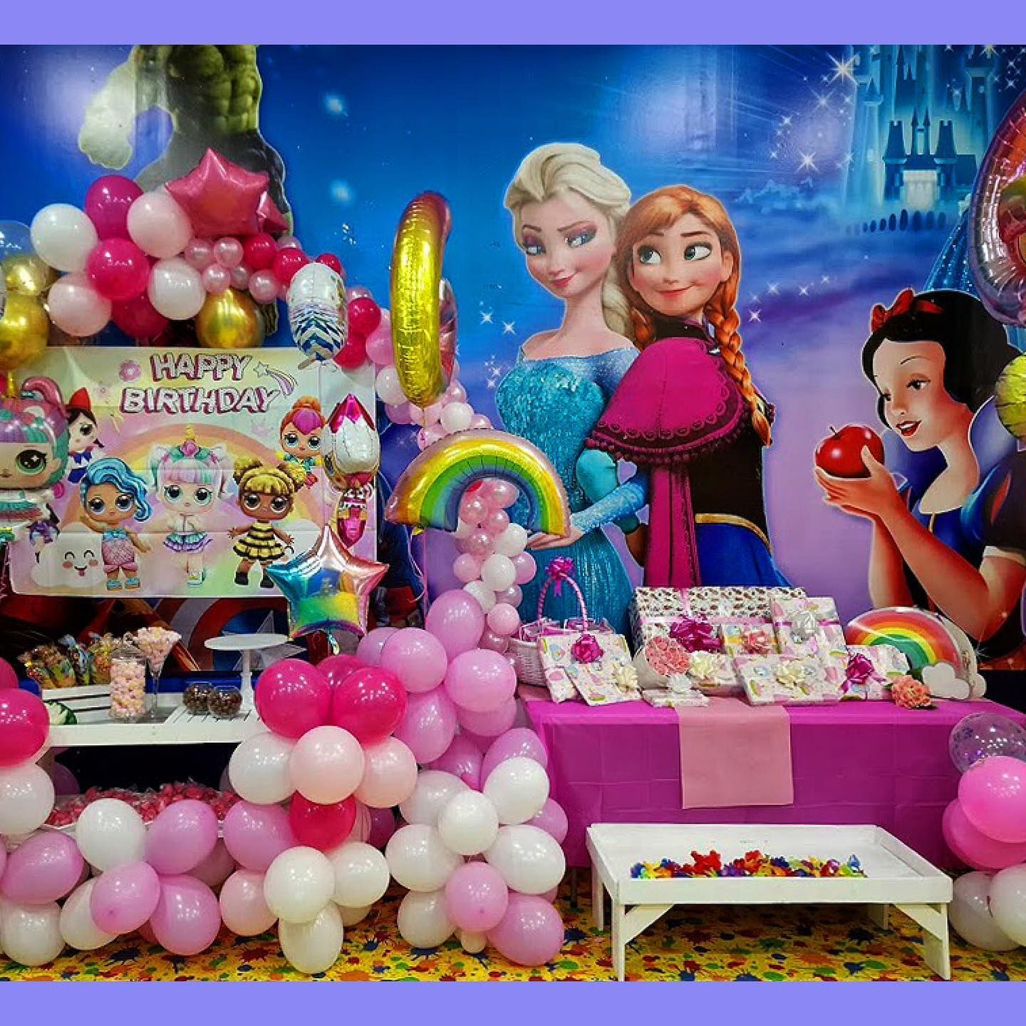 Montaje de fiesta de cumpleaños con personajes de dibujos animados, globos rosas y blancos y una mesa de juegos.