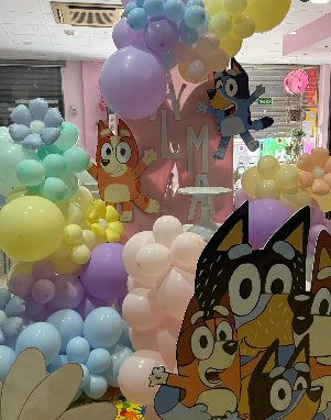 Decoraciones de fiesta con temática azul con globos en colores pastel; personajes recortados y el nombre 