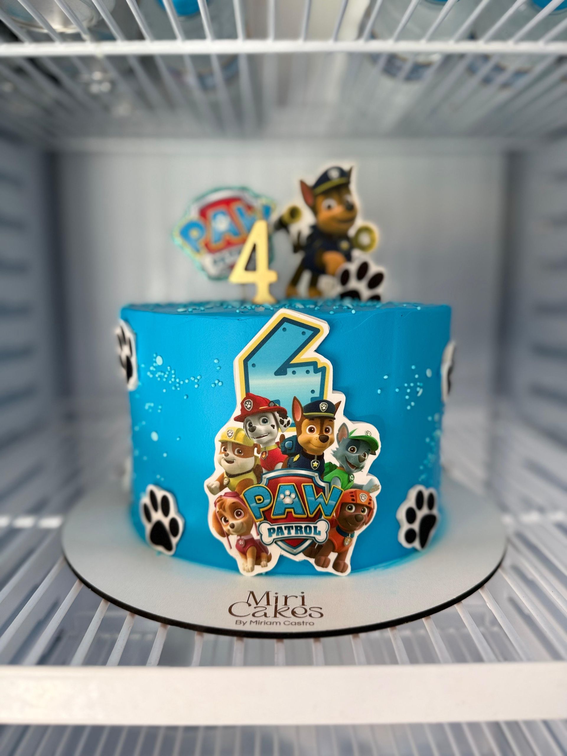 Pastel de cumpleaños de Paw Patrol azul con decoraciones y el número 4.