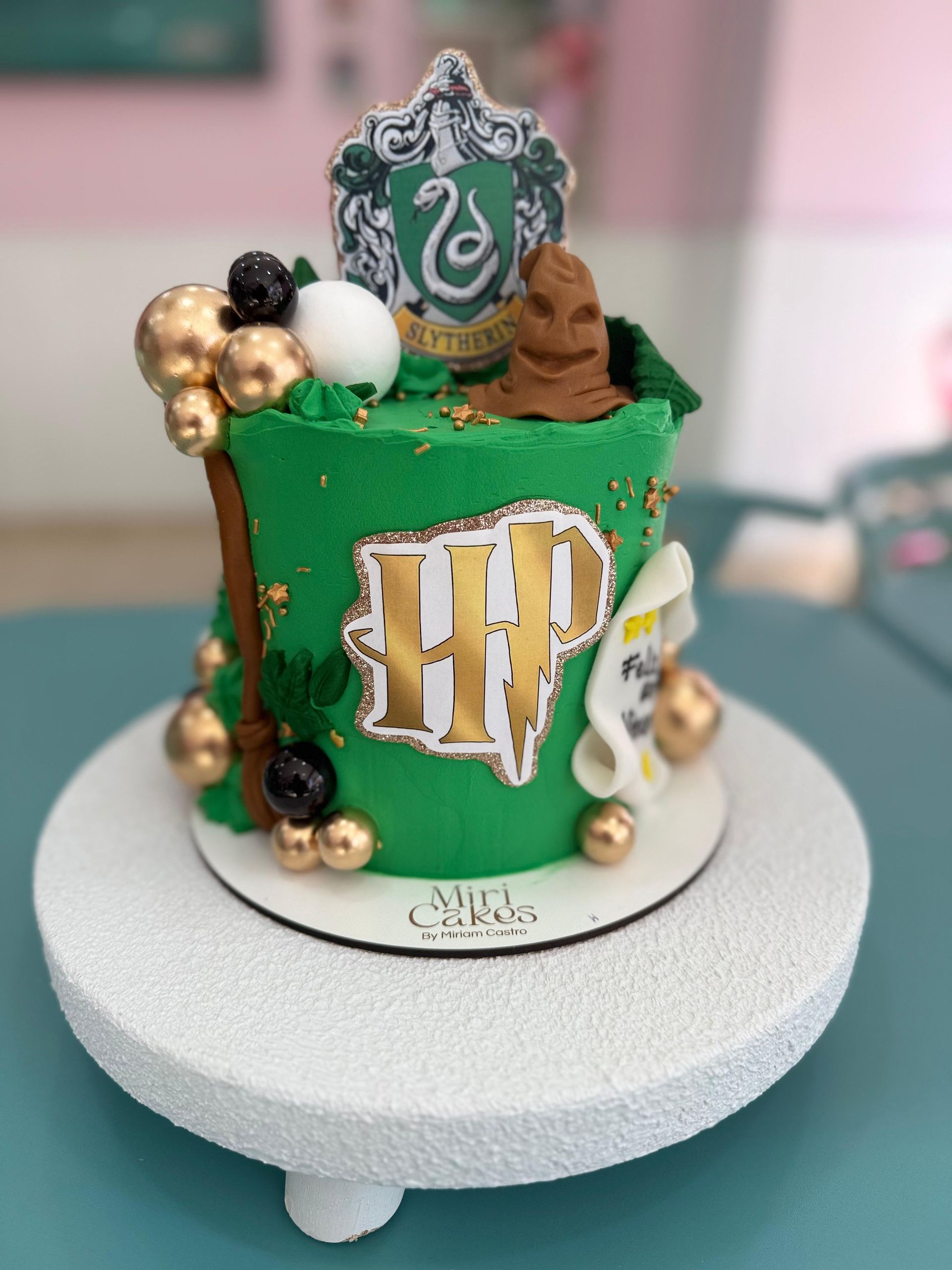 Pastel con temática de Harry Potter con glaseado verde, detalles dorados y un escudo de Slytherin.