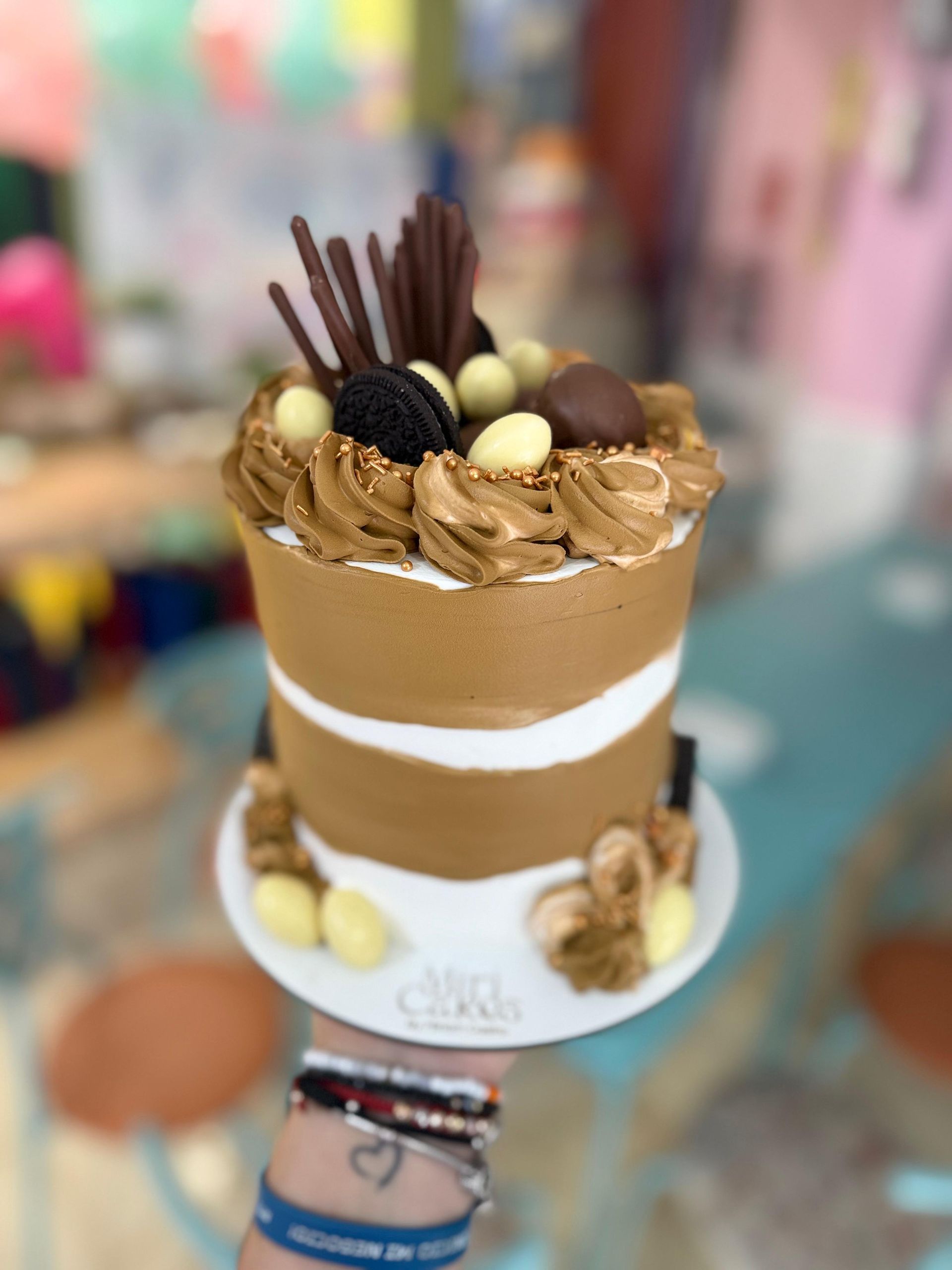 Pastel de chocolate con capas de glaseado blanco, cubierto con decoraciones de chocolate y bolas de chocolate blanco.